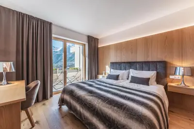 a hotel room with a bed and a desk and a window at Charming Suite by Dornsberg Panoramic Apartments in Schenna