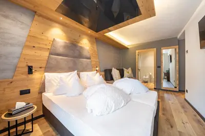 a bedroom with a large white bed with a wooden wall at Suite del Podesta' in Moena