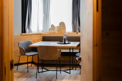 a table and chairs in a room with a window at Suite del Podesta' in Moena