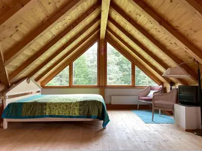 a bedroom with a bed and a large window at Chalet am Waldrand in Verano