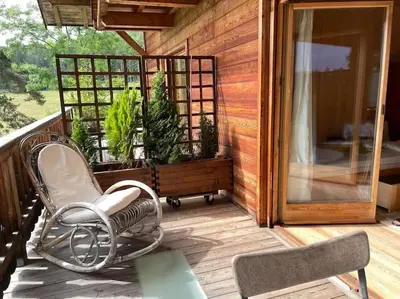 a rocking chair on a porch with potted plants at Chalet am Waldrand in Verano