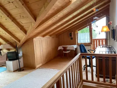 a wooden cabin with a balcony with a table and chairs at Chalet am Waldrand in Verano