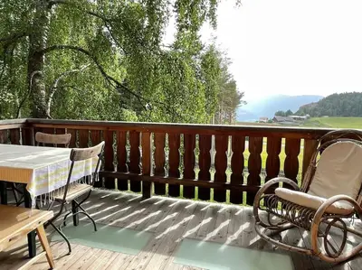 a patio with a table and chairs on a deck at Chalet am Waldrand in Verano