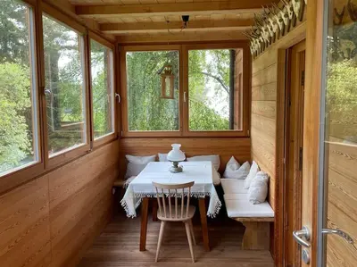 a dining room with a table and two windows at Chalet am Waldrand in Verano