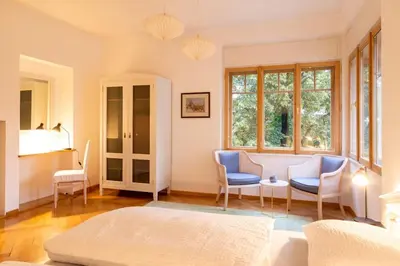 a bedroom with a bed and two chairs and a table at Cityappartment Villa Landeck in Merano