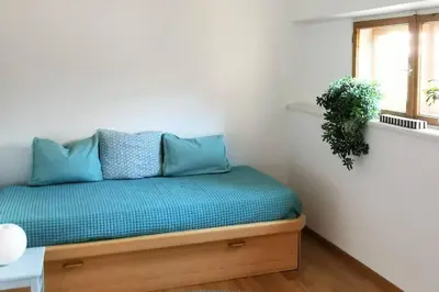 a bedroom with a bed with blue pillows and a window at Cityappartment Villa Landeck in Merano