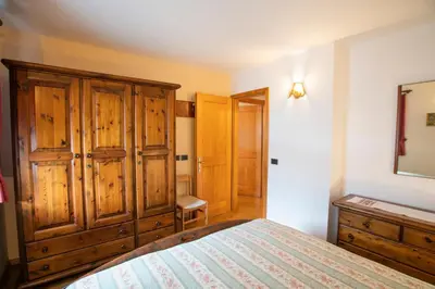 a bedroom with a bed and a wooden cabinet at Villa Rosa in Vigo di Fassa
