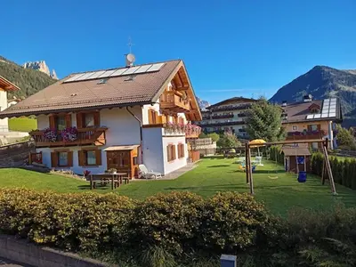 a building with a yard with a playground at Villa Rosa in Vigo di Fassa