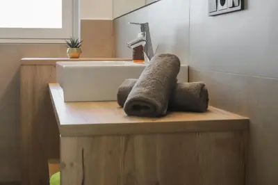 a bathroom with a sink and towels on a wooden counter at Justina 7 Apartments in San Paolo