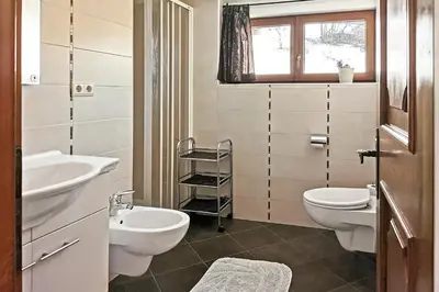 a bathroom with two sinks and a toilet and a window at Moosbachhof - Ferienwohnung Marienkäfer in Collalbo