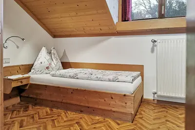 a bed in a room with a wooden floor at Moosbachhof - Ferienwohnung Marienkäfer in Collalbo