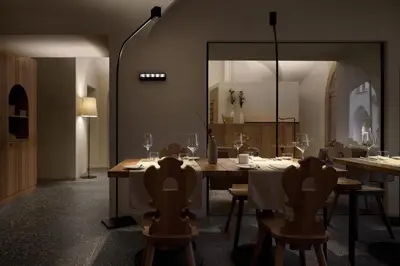a dining room with a table and chairs and a mirror at fink Restaurant & Suites in Brixen