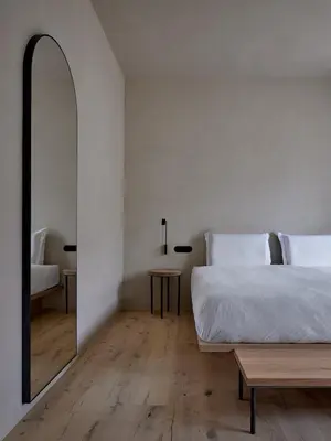 a bedroom with a bed and a mirror and a table at fink Restaurant & Suites in Brixen
