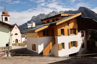 a building in front of a church with mountains in the background at Casa Latemar in Moena