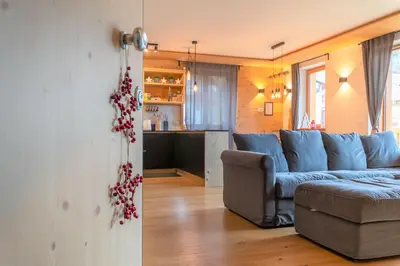a living room with a blue couch and a kitchen at Casa Mari in Falcade
