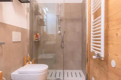 a bathroom with a toilet and a glass shower at Casa Mari in Falcade