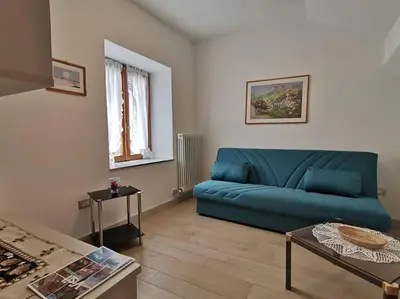 a living room with a blue couch and a table at Verde di Valda in Valda