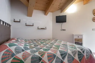 a bedroom with a colorful quilt on a bed at DolomiApartments - Appartamento Coronelle in Predazzo