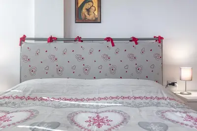 a bed with hearts on it with a head board at DolomiApartments - Appartamento Coronelle in Predazzo
