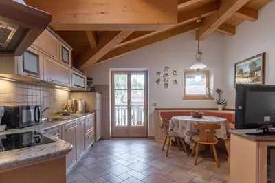 a kitchen with a table and a dining room at DolomiApartments - Appartamento Coronelle in Predazzo