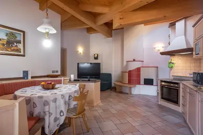 a kitchen with a table and a television in a room at DolomiApartments - Appartamento Coronelle in Predazzo