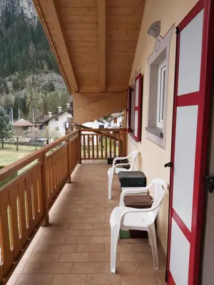 a balcony with two white chairs and a window at DolomiApartments - Appartamento Coronelle in Predazzo