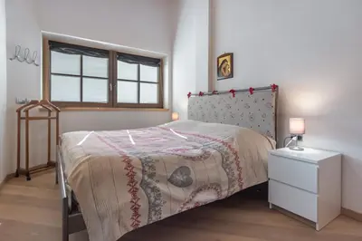 a bedroom with a bed and a dresser and a window at DolomiApartments - Appartamento Coronelle in Predazzo