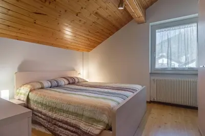 a bedroom with a bed with a wooden ceiling at DolomiApartments - Casa Lagorai in Predazzo