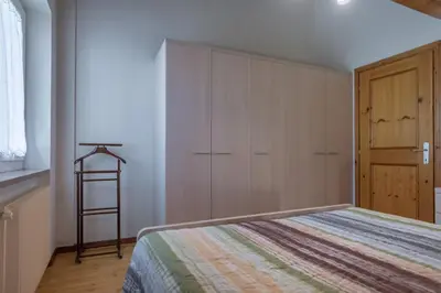 a bedroom with a bed and a wooden cabinet at DolomiApartments - Casa Lagorai in Predazzo