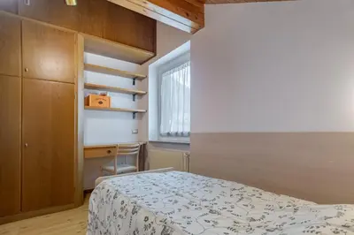 a small bedroom with a bed and a window at DolomiApartments - Casa Lagorai in Predazzo