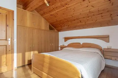a bedroom with a large bed with a wooden ceiling at DolomiApartments - Casa Lagorai in Predazzo