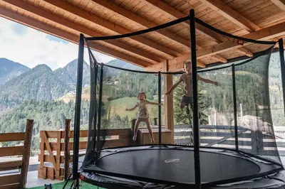 two people jumping on a trampoline in a house at Hinterscholerhof in Lazfons