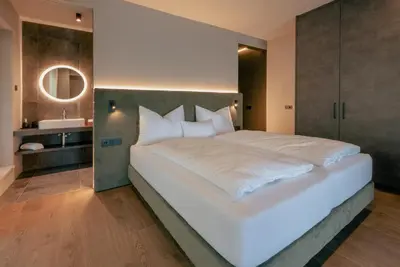 a bedroom with a large white bed and a bathroom at La Libella - Suite #5 - la terrazza mit privatem Pool in Merano