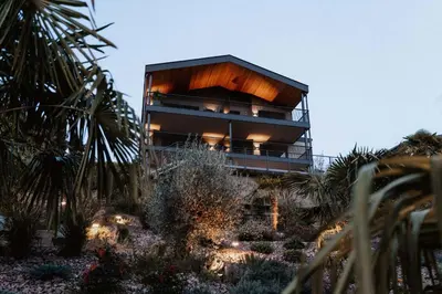 a building on a hill with palm trees and lights at La Libella - Suite #5 - la terrazza mit privatem Pool in Merano