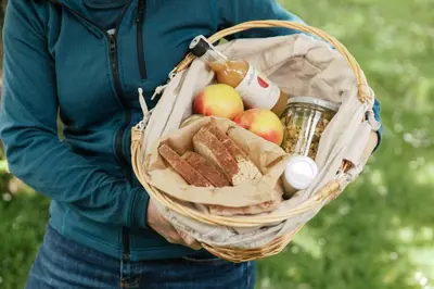 a person holding a basket of food and apples at Dolomitihouse NOGHERA in Fiera di Primiero