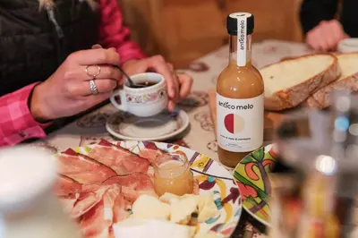 a person sitting at a table with a bottle of wine at Dolomitihouse NOGHERA in Fiera di Primiero