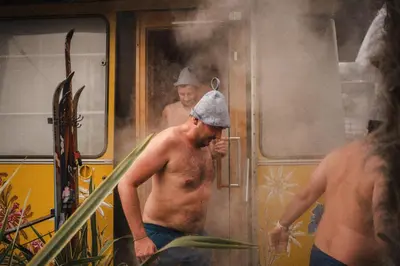 two shirtless men standing outside of a train at Hosler in Merano