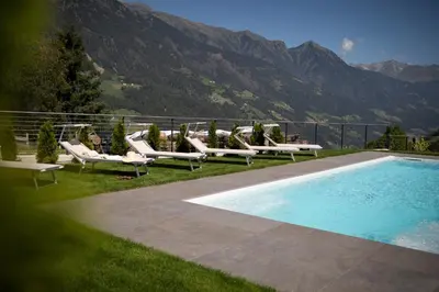 a group of lounge chairs next to a swimming pool at Natur Residence Kaiser Hans in Schenna