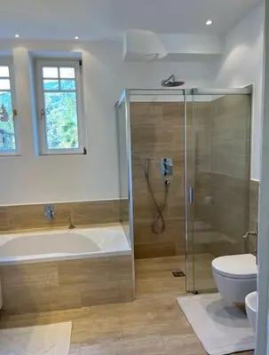 a bathroom with a shower and a tub and a toilet at Laurelia Suites in Merano