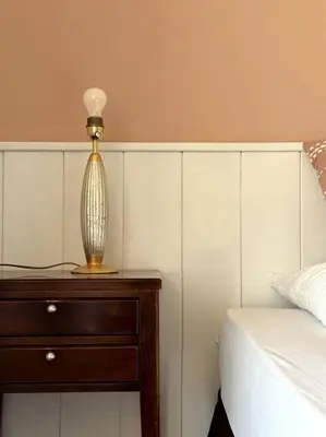 a lamp on a wooden table next to a bed at Laurelia Suites in Merano