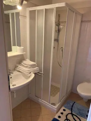 a white bathroom with a shower and a sink at Santlhof-Chardonnay in Cortaccia
