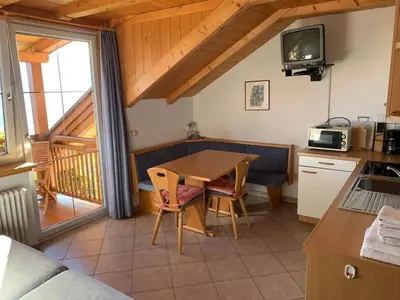 a kitchen and dining room with a table and a balcony at Santlhof-Chardonnay in Cortaccia
