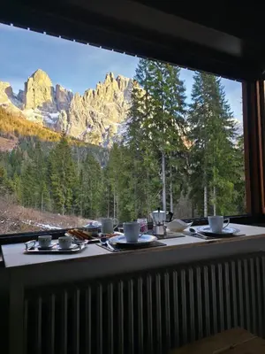 a table with a view of mountains from a window at Hope Home Trentino in San Martino di Castrozza