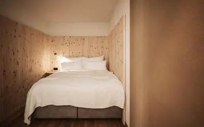 a bedroom with a white bed with a wooden wall at Milla Apartments in Bressanone