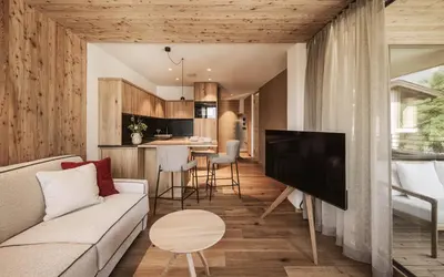 a living room with a couch and a tv and a kitchen at Milla Apartments in Bressanone