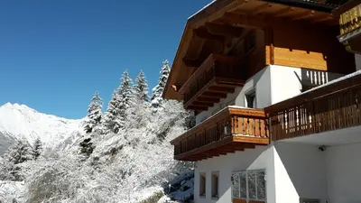 a building with snow covered trees and a mountain at Pixnerhof Urlaub auf dem Bauernhof in Schenna