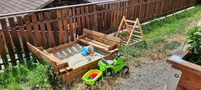 a wooden sandbox with a toy truck and a fence at Pixnerhof Urlaub auf dem Bauernhof in Schenna
