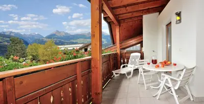 a balcony with a table and chairs and mountains at Stoanpeppelehof in Naz-Sciaves