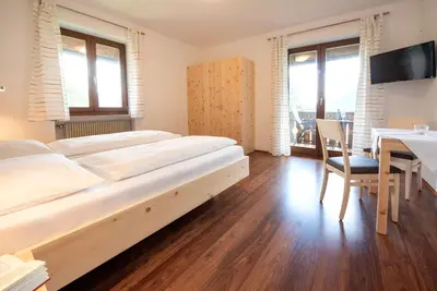 a bedroom with a large bed and a table with a chair at Eich-hof in Caldaro