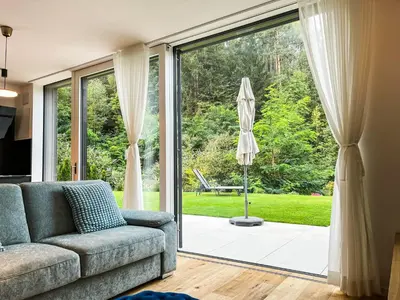 a living room with a couch and a sliding glass door at Garden Apartment Untermühle in Bressanone